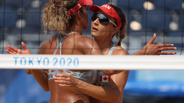 Deux joueuses de volleyball de plage se font l'accolade après avoir remporté un point pendant un match.
