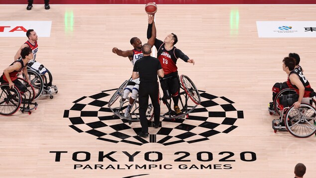 Assis dans leur fauteuil roulant respectif, deux joueurs ont tendu leur bras pour s'emparer du ballon pour créer un jeu offensif. 