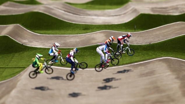 Des cyclistes de BMX sont dans les airs pendant une course après avoir sauté d'une bosse. Elles sont sur le point d'atterrir sur une seconde bosse.