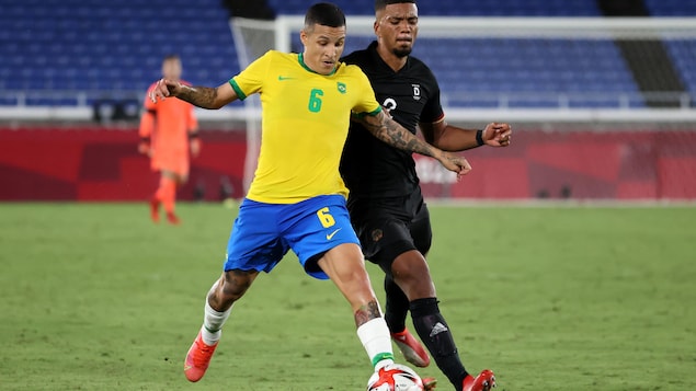 Guilherme Arana #6 de l'équipe du Brésil tente de se démarquer afin de garder la possession du ballon avec Benjamin Henrichs #2 de l'équipe de l'Allemagne.