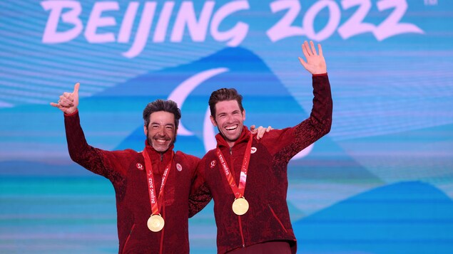Le para-athlète Brian McKeever et son guide saluent la foule en portant fièrement leur médaille d'or au cou.