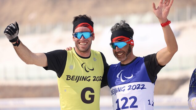 Le parafondeur Brian McKeever et son guide lèvent les bras et saluent la foule en célébration.