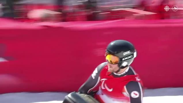 Brian Rowland freine sur son paraski assis au bas de la piste.