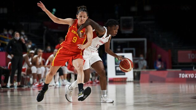 Une joueuse de l'équipe canadienne de basketball drible en bloquant son adversaire espagnole.