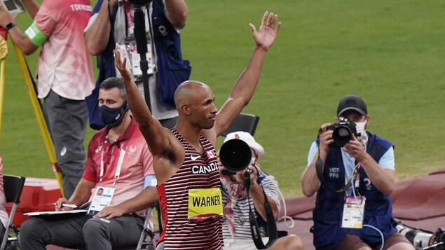 Damian Warner celebrates with his arms raised after his first javelin throw.