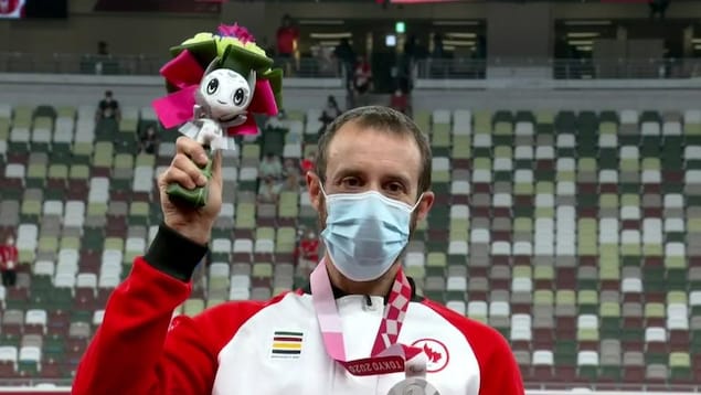 Brent Lakatos tient son bouquet ainsi que sa médaille d'argent accrochée à son cou.