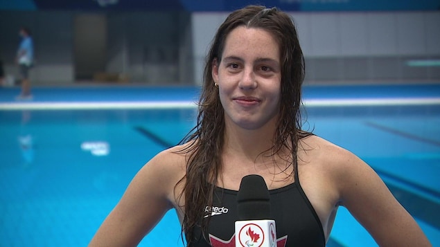 La nageuse Aurélie Rivard accorde une entrevue devant la piscine.