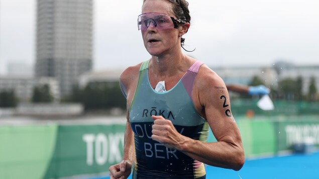Une coureuse en pleine action en triathlon aux Jeux de Tokyo s'apprête à franchir la ligne d'arrivée.