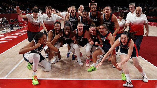 French players pose, all smiles, on the basketball court.