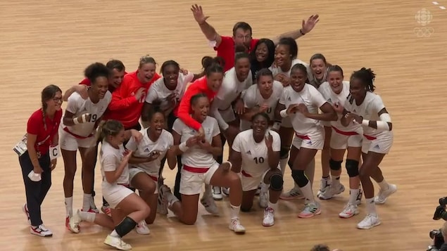 Toutes les joueuses de l'équipe de handball de la France sourient à pleines dents alors qu'elles sont entourées des entraîneurs pour la prise d'une photo d'équipe après leur victoire en grande finale.