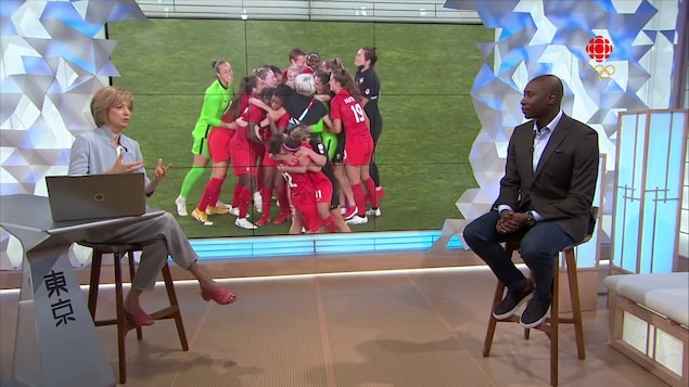 Deux animateurs devant un écran dans un studio de télévision.
