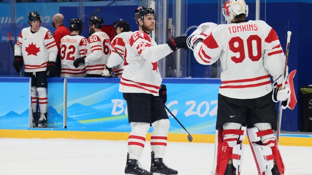 Un gardien de but et un joueur de hockey se tapent le poing. 