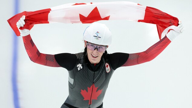 La patineuse Ivanie Blondin brandit le drapeau canadien au-dessus de sa tête.