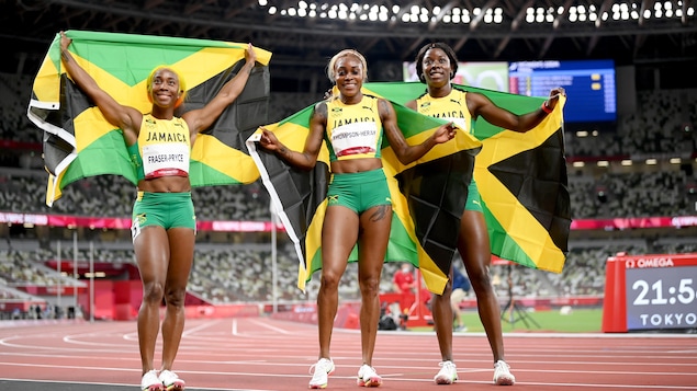 Shelly-Ann Fraser-Pryce (gauche), Elaine Thompson-Herah (centre) et Shericka Jackson (droite) brandissent chacune un drapeau jamaïcain à la suite de leur triplé olympique au 100 m.
