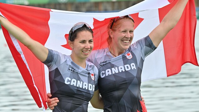 Deux athlètes sourient avec le drapeau canadien