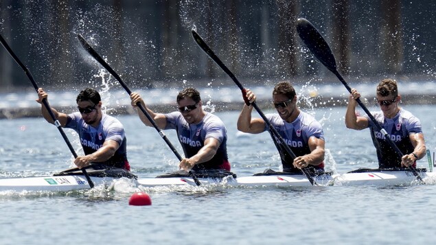 Les quatre kayakistes canadiens pagaient de façon coordonnée. La partie gauche de leur pagaie est dans l'eau.