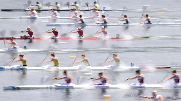 Les huit embarcations de la course se disputent la première place. La photo montre les kayakistes en action, on devine le mouvement des pagaies par le flou artistique de la photo.