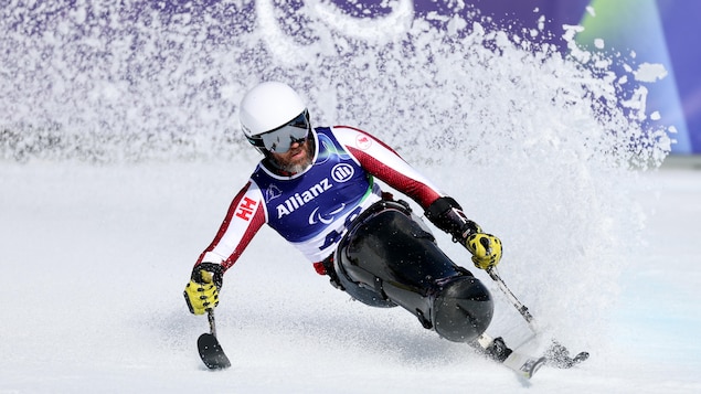 Kurt Oatway freine au terme de la descente en position assise aux Jeux paralympiques de Milan-Cortina. 