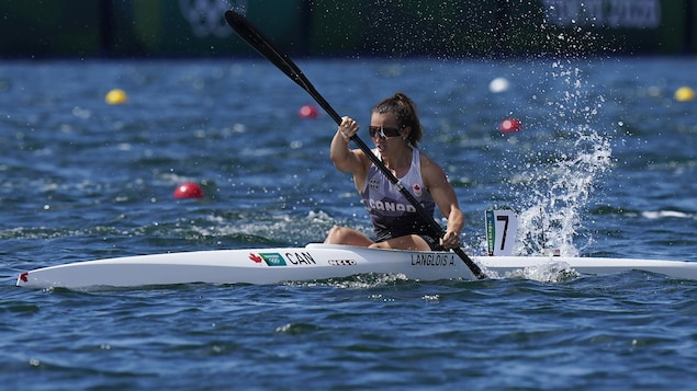 Andréanne Langlois est dans son kayak et pagaie, la moitié gauche de sa pagaie est dans l'eau.