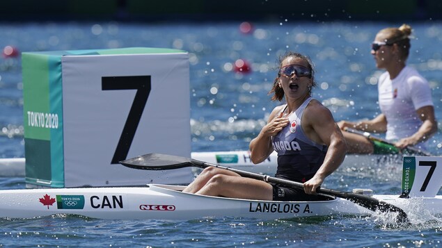 À bord de son kayak, Andréanne Langlois a l'air surprise et contente. Elle a la bouche ouverte et sa main droite est sur son coeur.