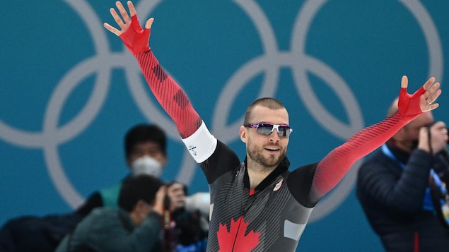 Le patineur Laurent Dubreuil lève les bras en célébration après une course qui lui a permis de remporter une médaille.