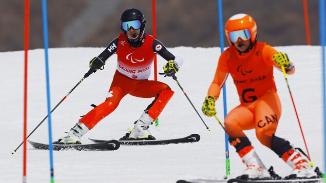 Le skieur guide Julien petit freine devant Logan Leach qui freine lui aussi entourés de portes.