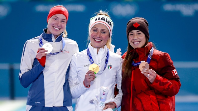 Valérie Maltais tient sa médaille de bronze en regardant la caméra.