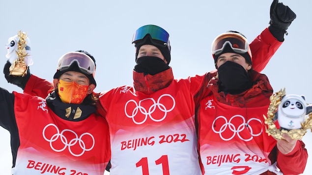 Trois athlètes lèvent les bras au ciel après leurs performances en planche à neige.