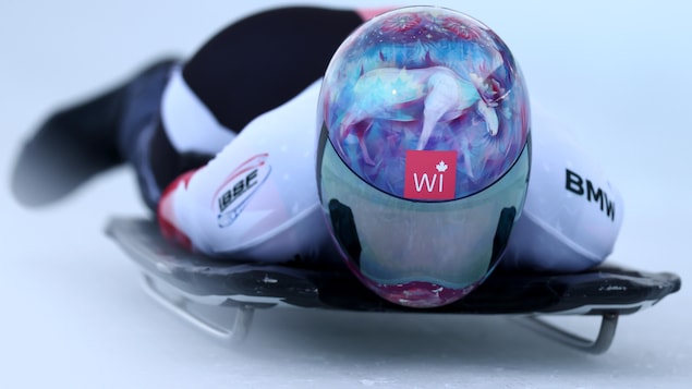 Une athlète est couchée sur le ventre sur son skeleton et glisse sur une piste glacée.