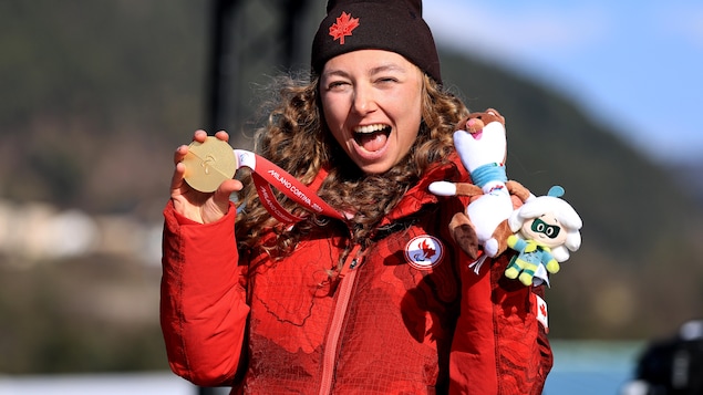 Natalie Wilkie, tout sourire, sur le podium paralympique avec sa médaille d'or à la main.