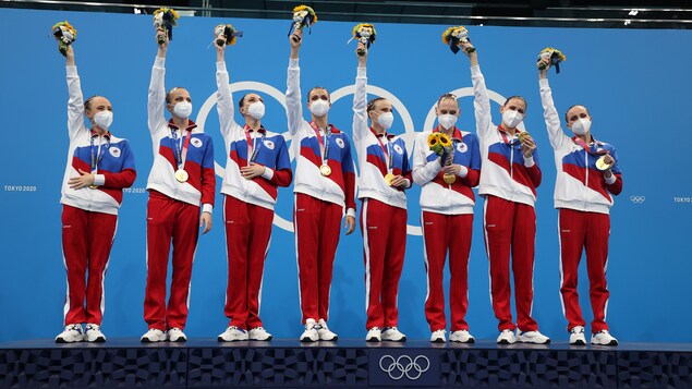 Les membres de l'équipe du Comité olympique russe brandissent leurs bouquets sur le podium.