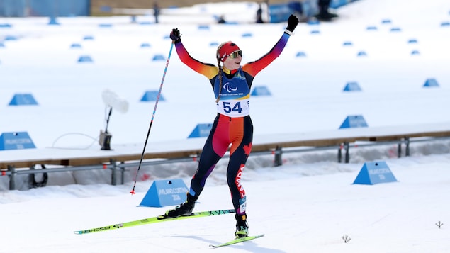 Natalie Wilkie lève les bras en souriant dans le dernier droit du sprint poursuite.