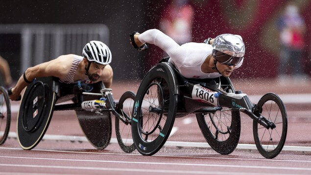 Les deux athlètes roulent rapidement sur la piste sous une pluie battante.
