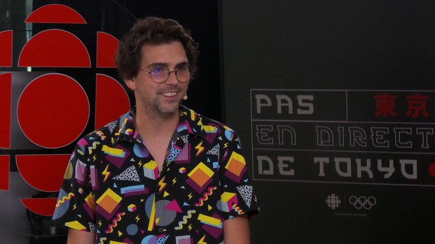 Un homme sourit lors d'une entrevue sur un plateau de tournage.