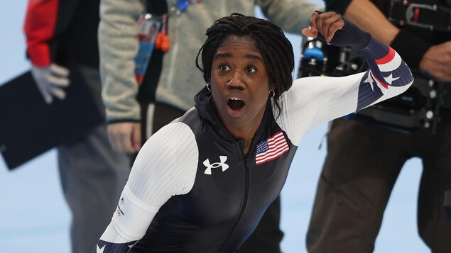 Erin Jackson, victorieuse, soulève le poing dans les aires.