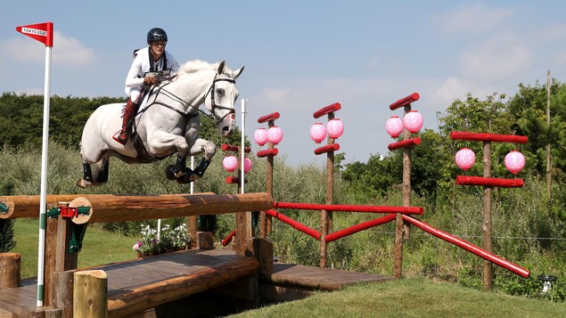 Colleen Loach sur son cheval Qorry Blue d'Argouges qui effectue un saut à l'épreuve du cross country aux Jeux olympiques de Tokyo 2020.