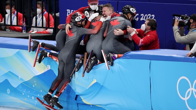 L'équipe de patinage du Canada célèbre une médaille en sautant par-dessus la bande.