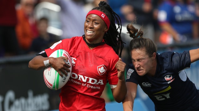 Charity Williams porte le ballon et bloque en courant la tentative de placage d'une adversaire.