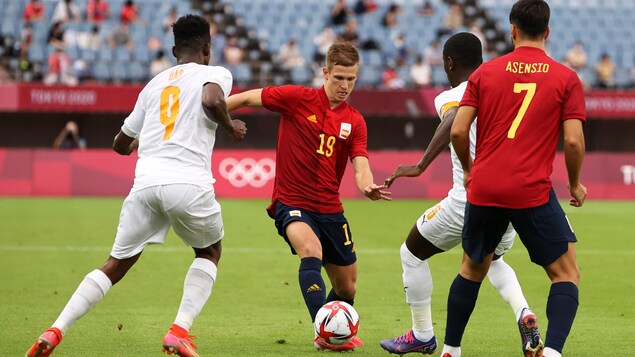 Dani Olmo dribblant entre deux joueurs de l'équipe ivoirienne.