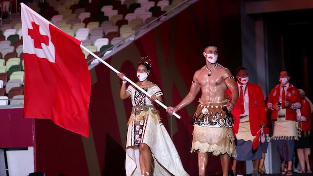 Pita Taufatofua, le torse nu et huilé, ainsi que Malia Paseka portent le drapeau du Tonga.