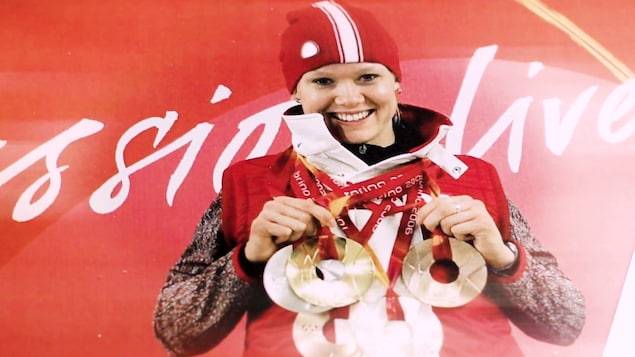 Cindy Klassen sur le podium tenant cinq médailles.