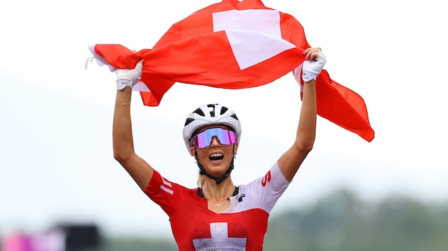Jolanda Neff qui célèbre sa victoire en tenant le drapeau suisse.