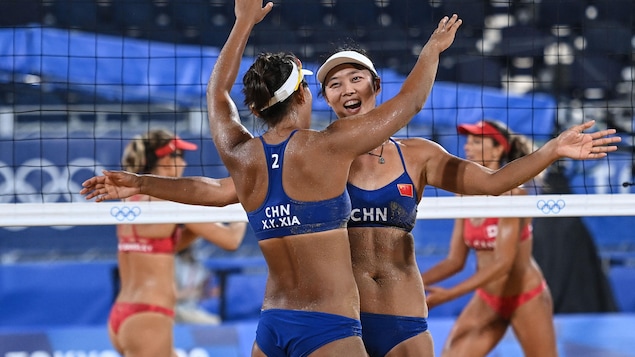 Xia Xinyi, une joueuse chinoise, s'approche de sa coéquipière Wang Fan afin de lui faire un câlin pour célébrer leur point. Derrière elles, les joueuses canadiennes, Brandie Wilkerson et Heather Bansley, vont vers l'une et l'autre pour se féliciter.