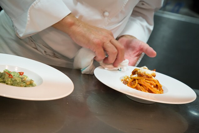 Un chef nettoie le bord d'une assiette de pâtes. Un chef nettoie le bord d'une assiette de pâtes.
