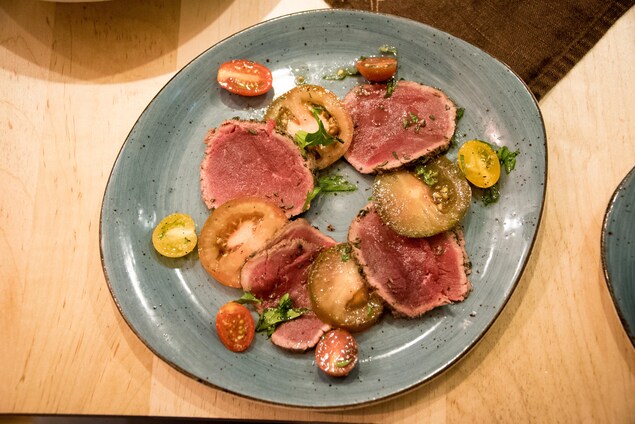 Une assiette qui contient des tranches de viande crue et des tomates Une assiette qui contient des tranches de viande crue et des tomates