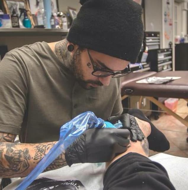 Un tatoueur en plein travail Un tatoueur en plein travail