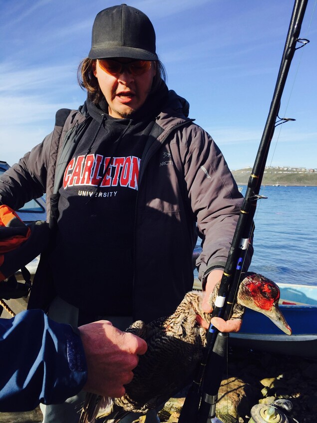 Robert Comeau, 22 ans, alors qu’il revient de la chasse aux phoques, descend de son bateau avec un canard qu’il tend fièrement. Robert Comeau, 22 ans, alors qu’il revient de la chasse aux phoques, descend de son bateau avec un canard qu’il tend fièrement.