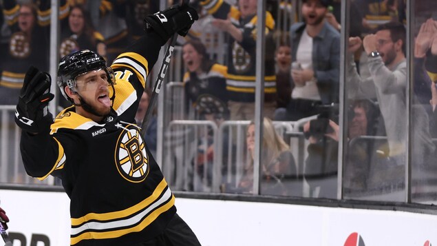 Un hockeyeur sort la langue et lève les bras.