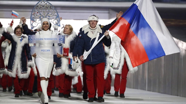 Il avance dans le stade devant ses coéquipiers russe et tient le drapeau dans ses mains.