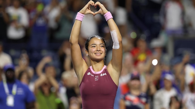 Une joueuse de tennis fait un signe de coeur avec les mains après avoir gagné son match